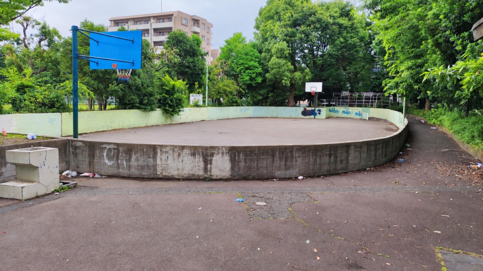 丸みのある壁に囲まれた北五公園の屋外バスケットコートと2基のゴール