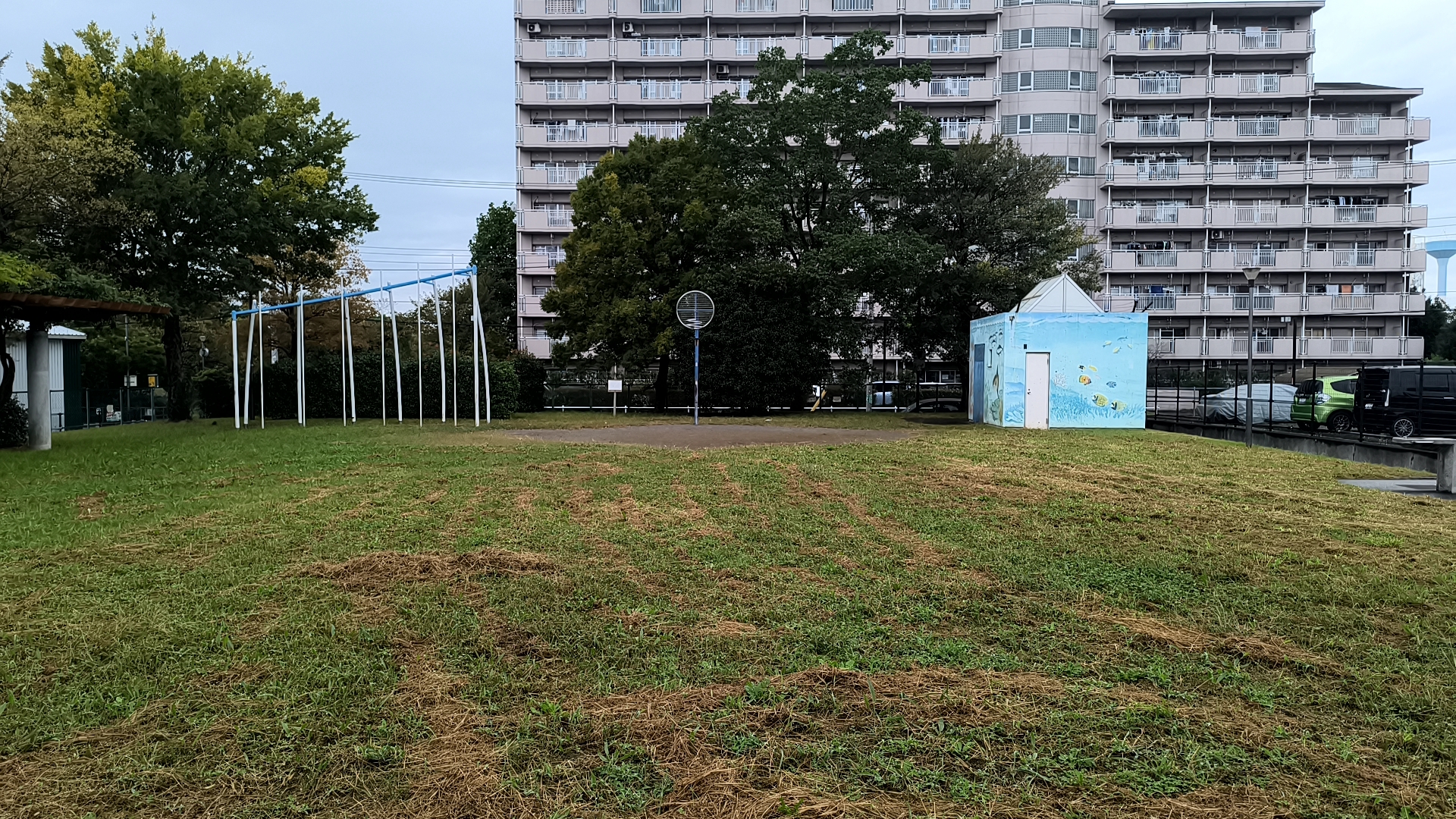 桑袋記念公園の広場、木々、遊具とバスケットゴール